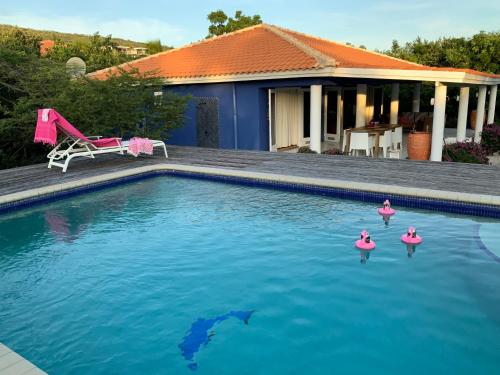 una piscina con flamencos de juguete en el agua en Villa 13, Coral Estate en Willibrordus