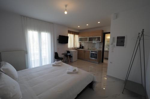 a bedroom with a large white bed and a kitchen at 5 Luxury Apartments Ioannina in Ioannina