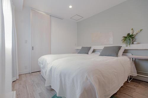 a white bedroom with a large bed and a desk at Asakusa YOSHII Designer Hotel in Tokyo
