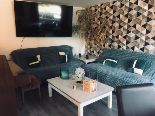 sala de estar con 2 sofás azules y TV en Auberge du relais d auniac Hotel Bar Restaurant Piscine en Anglars-Nozac