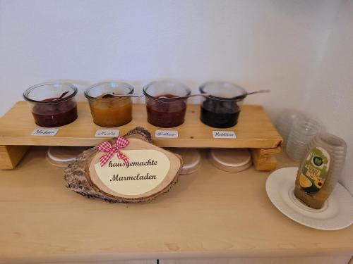 a wooden table with four jars of jam and a plate at Lärchenhof Serfaus in Serfaus