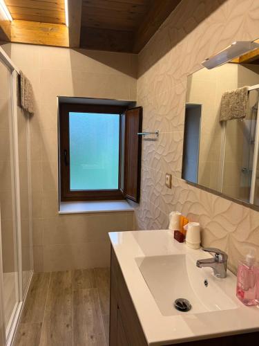 a bathroom with a sink and a mirror and a window at VILLA BERENGUELA in Boca de Huérgano