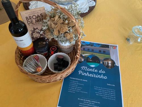 a basket with a bottle of wine and a magazine at Monte do Pinheirinho in São Domingos