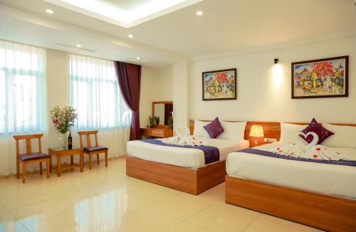 een hotelkamer met 2 bedden en een tafel en stoelen bij Aloha Hotel in Hanoi