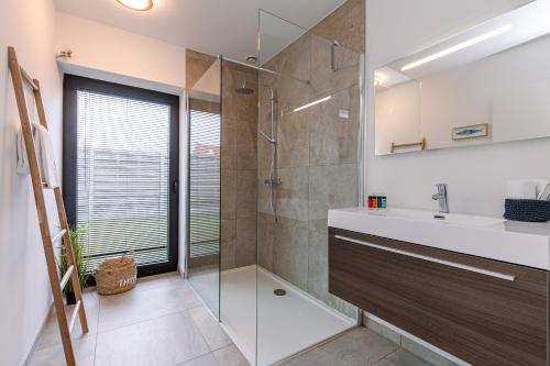 a bathroom with a shower and a sink and a mirror at Whaaw Westende-bad in Middelkerke