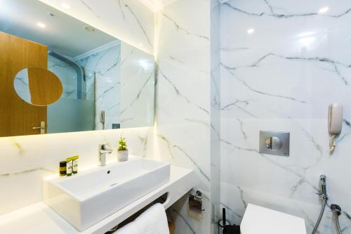 a white bathroom with a sink and a mirror at Menta City Boutique Hotel in Rethymno Town