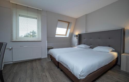a bedroom with a large bed and a window at Fletcher Zuiderduin Beachhotel in Westkapelle