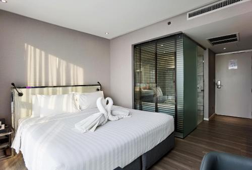 a bedroom with a bed with a white ribbon on it at Citrus Grande Hotel Pattaya by Compass Hospitality in Pattaya South