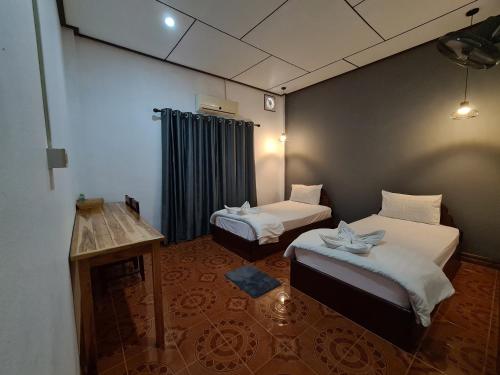 a room with two beds and a table in it at Saphaothong guesthouse in Vang Vieng