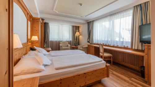 - une chambre avec un grand lit et une télévision dans l'établissement Hotel Armin, à Selva di Val Gardena