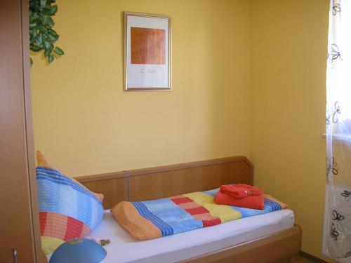 a small bedroom with a bed with a picture on the wall at Pension Lindenallee in Neuendettelsau