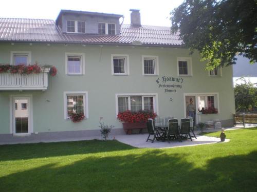 Gästehaus Hoamat'l في باخ: منزل أبيض مع طاولة وكراسي في الفناء