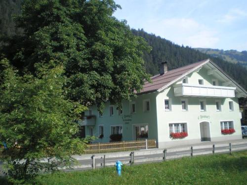 a large white building on a road with a tree at Gästehaus Hoamat'l in Bach