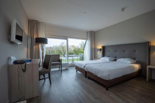 - une chambre avec un lit, un bureau et une fenêtre dans l'établissement Fletcher Zuiderduin Beachhotel, à Westkapelle