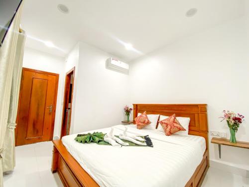 a bedroom with a bed with white sheets and flowers at Bliss & Beats Hostel in Phnom Penh