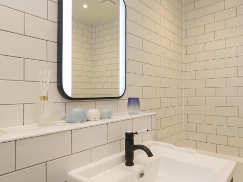 Baño blanco con lavabo y espejo en Saxon Princess Suite, en Saltburn-by-the-Sea