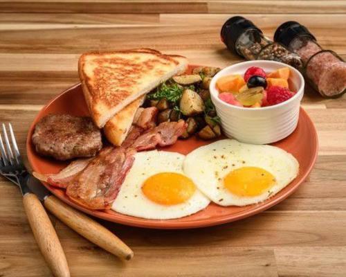 a plate of breakfast food with eggs sausage and toast at Banorupa Kuakata hotel in Kuākāta
