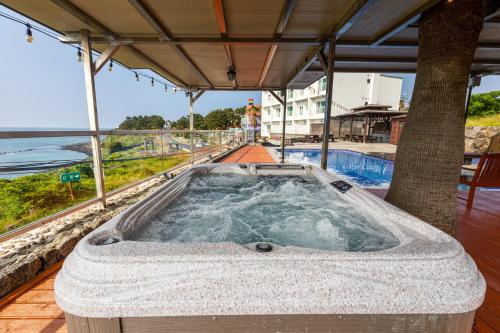a jacuzzi tub on a deck next to a pool at Aewol Oceanstay in Jeju