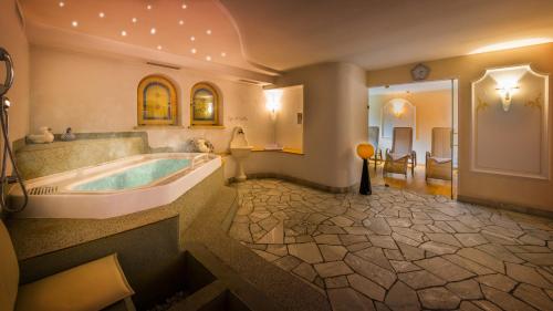 a large bathroom with a tub and a sink at Hotel Armin in Selva di Val Gardena