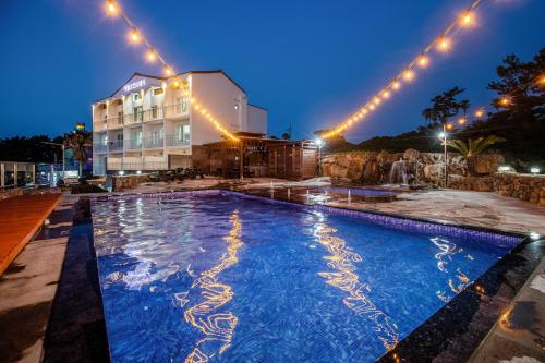 a swimming pool in front of a building at night at Aewol Oceanstay in Jeju