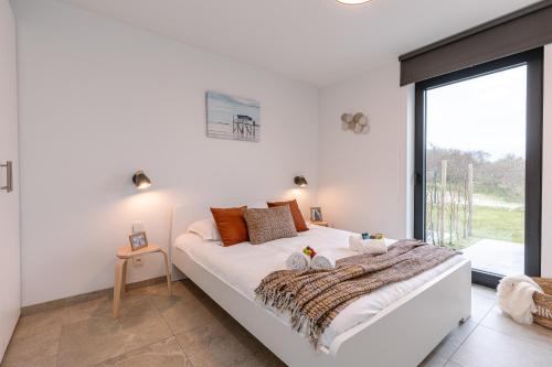 a white bedroom with a large bed and a large window at Whaaw Westende-bad in Middelkerke