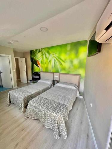 two beds in a room with a painting on the wall at Hostal Viena Plaza Nueva in Granada