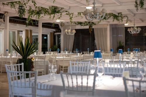a room filled with white tables and chairs at Hotel La Cavalera in Augusta