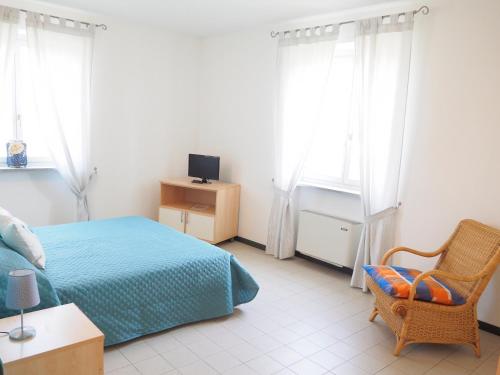 a bedroom with a bed and a chair and windows at Mini-Appartamenti, Camere Lanterna Blu in Mombello Monferrato