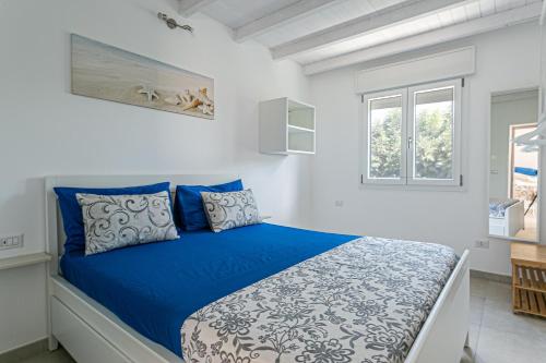 a bedroom with a bed with blue sheets and a window at Resort Almaredamarra con piscina e idromassaggio sul mare in Torre San Giovanni Ugento