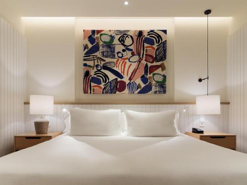 a bedroom with a large white bed with two lamps at H10 Croma Málaga in Málaga