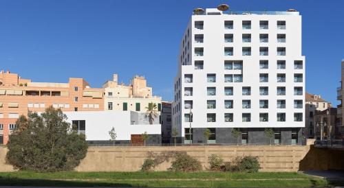 a tall white building in a city with buildings at H10 Croma Málaga in Málaga