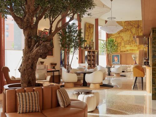 a lobby with a tree and chairs and a table at H10 Croma Málaga in Málaga