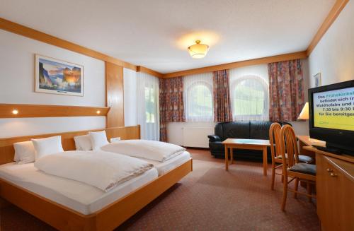 a hotel room with a bed and a television at Der Waldhof in Scheffau am Wilden Kaiser