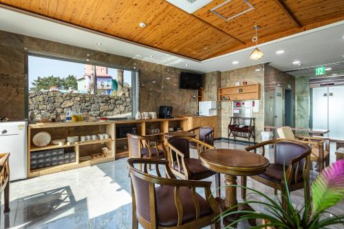 a restaurant with wooden ceilings and tables and chairs at Aewol Oceanstay in Jeju