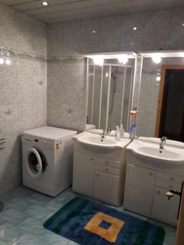 a bathroom with a washing machine and two sinks and a washer at Sieglhof in Breitenbach am Inn