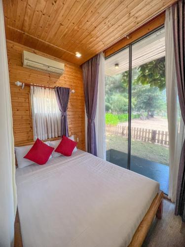 a bedroom with a bed with red pillows and a window at Long Hải Channel Beach Resort in Long Hai