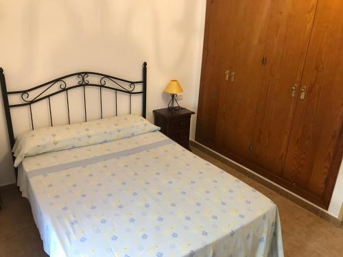 a bedroom with a bed and a dresser with a lamp at Conil Colorado 1 rústico y económico in Conil de la Frontera