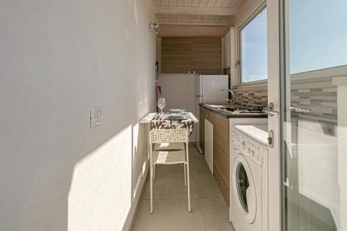 een keuken met een tafel en een wasmachine bij Resort Almaredamarra con piscina e idromassaggio sul mare in Torre San Giovanni Ugento
