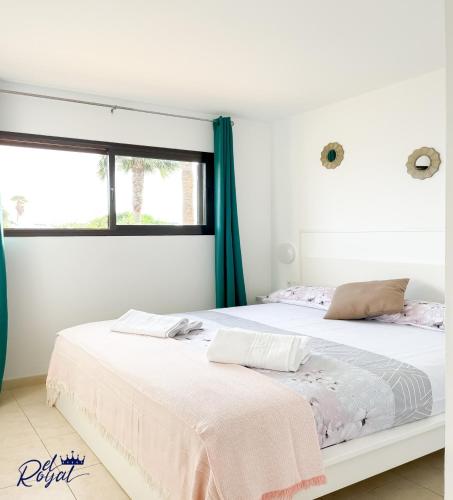 a white bedroom with a large bed with a window at B-Rent El Royal Corralejo in Corralejo