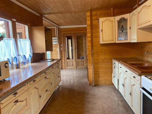 Il comprend une grande cuisine avec des murs en bois et des placards blancs. dans l'établissement Chalet chaleureux, à Billy