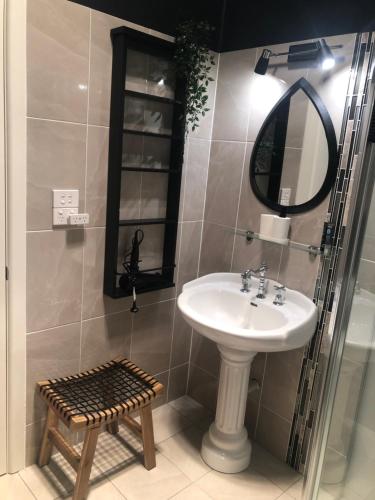 uma casa de banho com um lavatório, um espelho e um banco em Maple Leaf Cottage em Dubbo