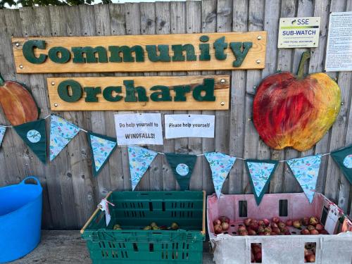 a sign that readscommunity orchard with apples in front of a fence at River house in Birnam
