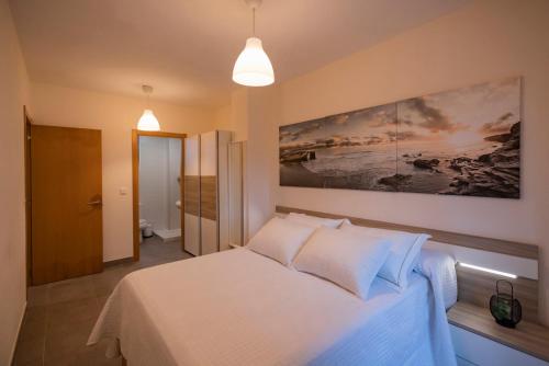 um quarto com uma cama branca e um quadro na parede em Area Suites em Jove