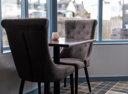 two chairs and a table in front of a window at GOLF View Hotel & Macintosh Restaurant in Lossiemouth