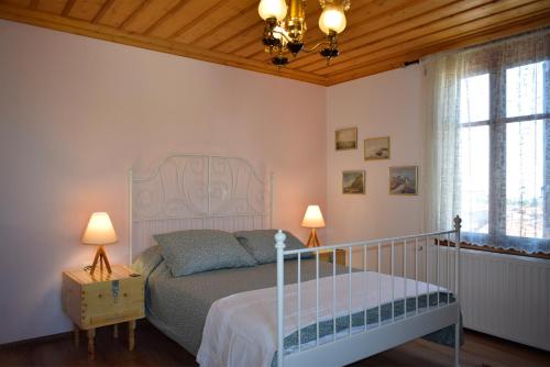 a bedroom with a bed and a chandelier and two lamps at Renovated Old Manor House With Yard in Arnaia