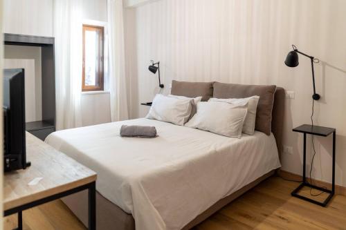 a bedroom with a large bed with white sheets and a television at I giardini del borgo in Vico nel Lazio