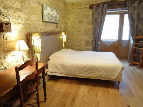 1 dormitorio con cama, mesa y ventana en Gite du tailleur, en Sébrazac
