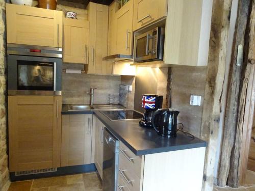 a kitchen with wooden cabinets and a counter top at Gite du tailleur in Sébrazac