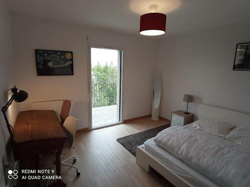 1 dormitorio con cama, escritorio y ventana en Superbe appartement avec balcon filant, en Cenon