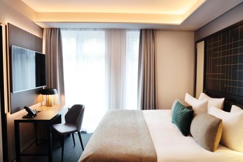 um quarto de hotel com uma cama, uma secretária e uma televisão em Hótel Reykjavík Saga em Reykjavík